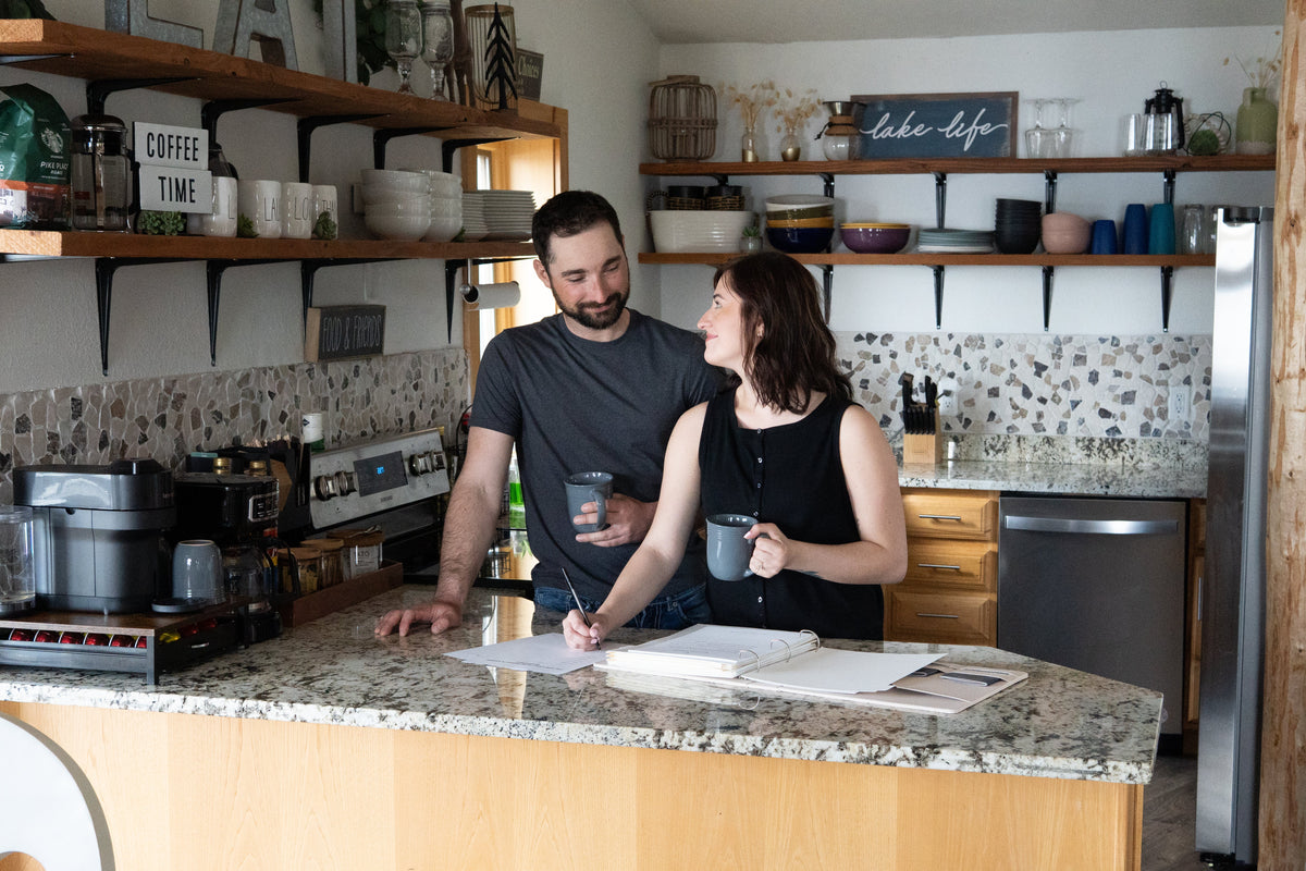 A married couple reviewing passwords and digital account information together on a laptop while organizing important documents at home.